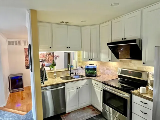 a view of a hallway with wooden floor and a refrigerator