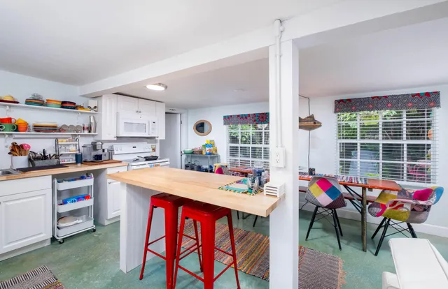 a open kitchen with stainless steel appliances kitchen island granite countertop a dining table chairs and a refrigerator