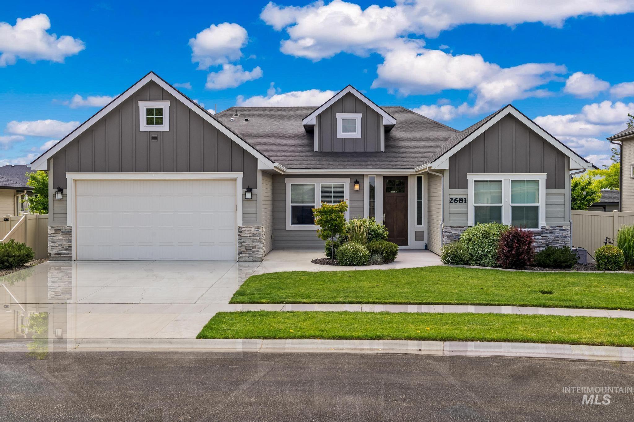 Contemporary ranch-style home featuring a two-car garage, mixed siding materials, stone accents, mature landscaping, and an inviting front entry