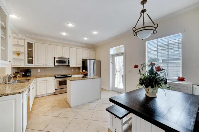 a kitchen with stainless steel appliances kitchen island granite countertop a refrigerator a stove a sink dishwasher a dining table and chairs with wooden floor