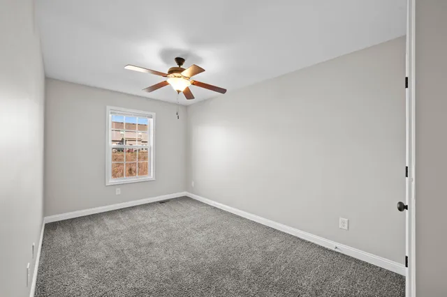 an empty room with a window and a fan