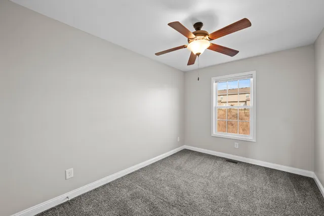an empty room with ceiling fan and window