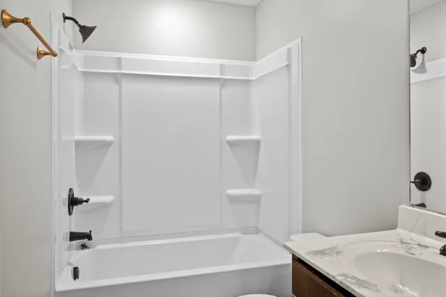 a bathroom with a granite countertop bathtub shower sink and toilet