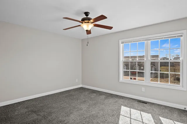 an empty room with window and ceiling fan
