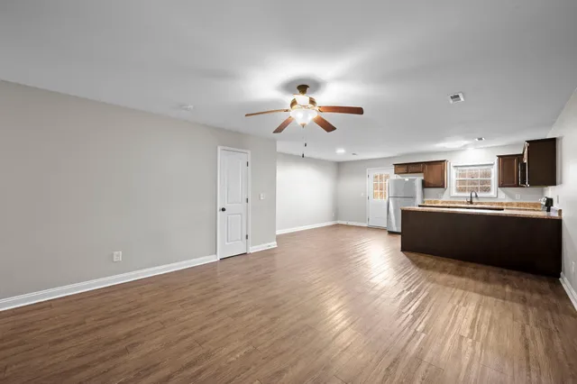 a view of a kitchen with a sink a refrigerator a ceiling fan and wooden floor