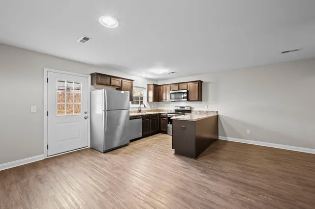 a kitchen with stainless steel appliances a refrigerator a sink dishwasher a oven with wooden floor