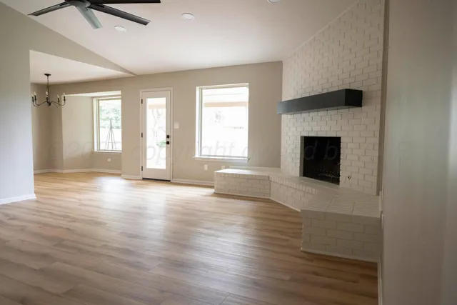 an empty room with wooden floor a fireplace and windows