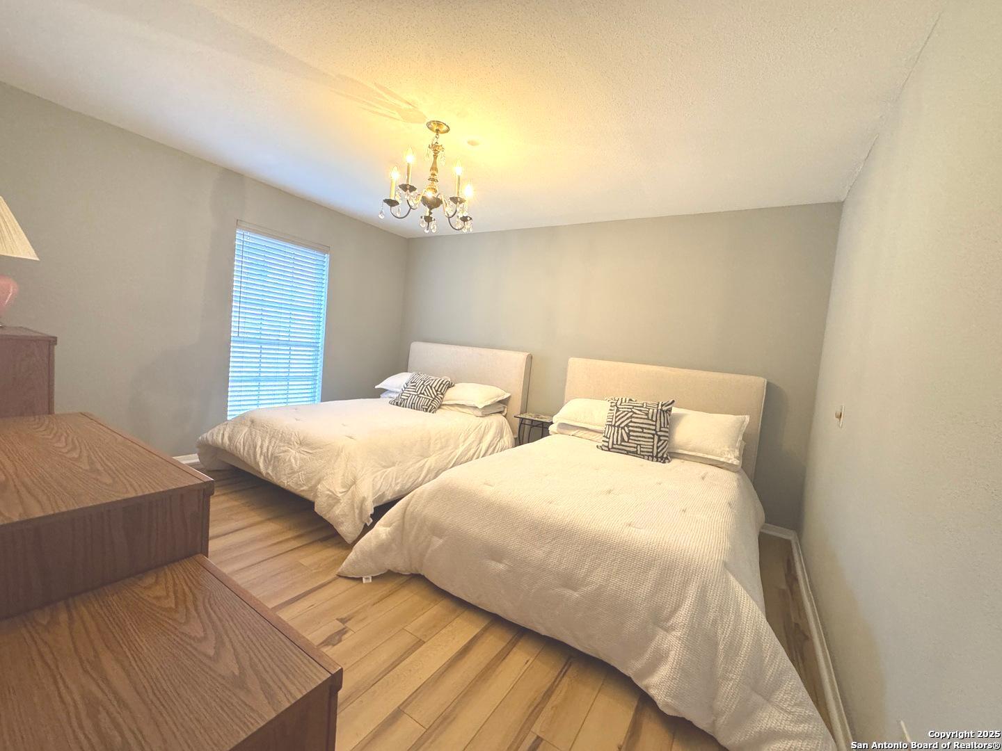 7500 Callaghan, Unit 254 San Antonio, TX 78229 - Photo 12 of 36 a bedroom with two beds and a chandelier