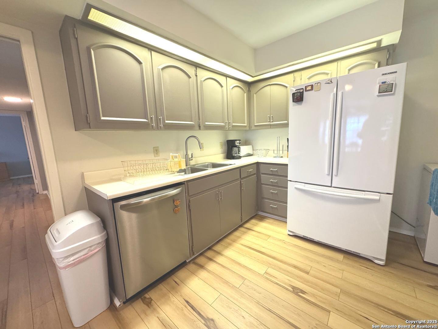 7500 Callaghan, Unit 254 San Antonio, TX 78229 - Photo 20 of 36 a kitchen with a refrigerator a sink and dishwasher with wooden floor