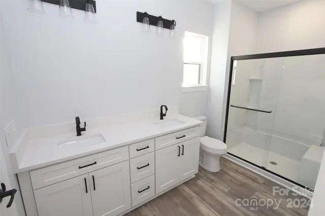 a bathroom with a double vanity sink toilet a shower and a mirror