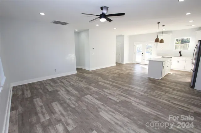 a view of kitchen and empty room with wooden floor