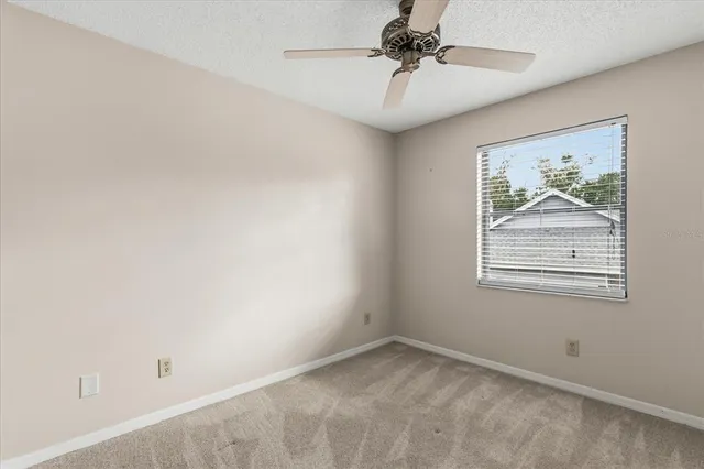 an empty room with a window and a fan