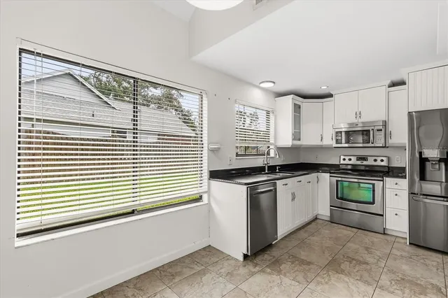 a kitchen with stainless steel appliances granite countertop white cabinets a sink and a stove