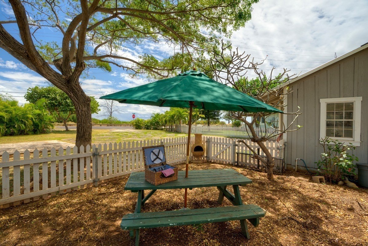 8706 Kiowea Road Kekaha, HI 96752 - Photo 26 of 30 a view of a patio with table and chairs under an umbrella with large trees