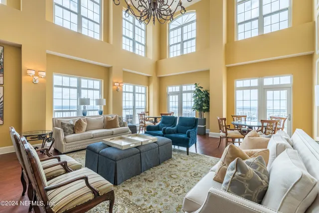 a living room with furniture large windows and wooden floor