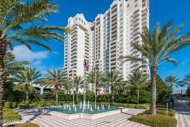 a view of a tall building with a palm tree and a yard