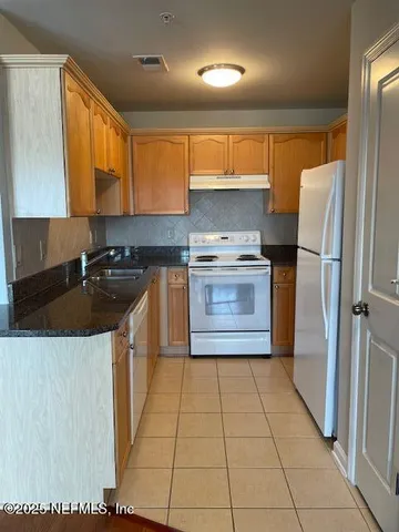 a kitchen with granite countertop a refrigerator and a stove top oven