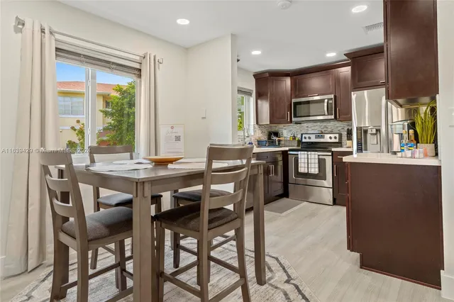 a dining hall with stainless steel appliances kitchen island granite countertop a dining table and chairs