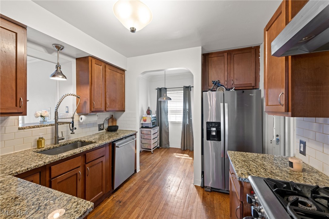 2471 Channing Road Cleveland, OH 44118 - Photo 8 of 33 Kitchen featuring a sink, arched walkways, stainless steel appliances, backsplash, and under cabinet range hood