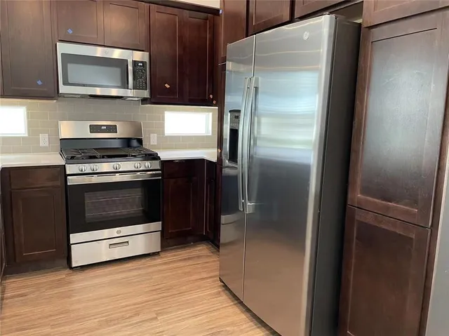 a kitchen with stainless steel appliances a refrigerator a sink a stove a microwave and wooden cabinets