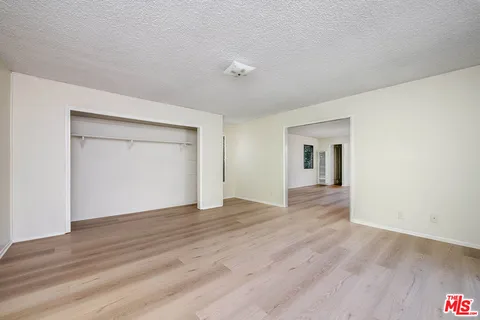 a view of an empty room with wooden floor and cabinet