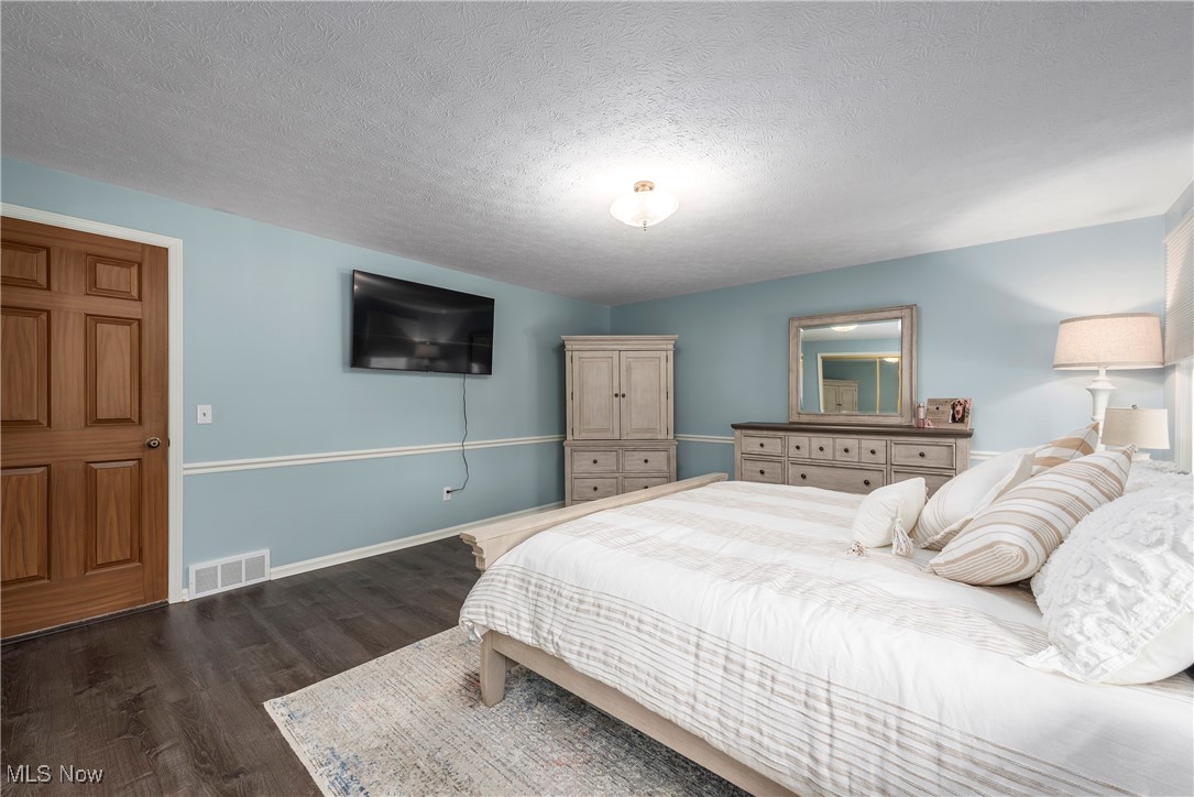 580 Orchardview Road Independence, OH 44131 - Photo 23 of 44 Bedroom with a textured ceiling, dark wood-style flooring, visible vents, and baseboards