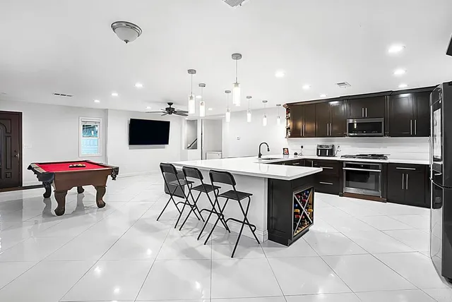 a kitchen with stainless steel appliances kitchen island granite countertop a table chairs sink and microwave