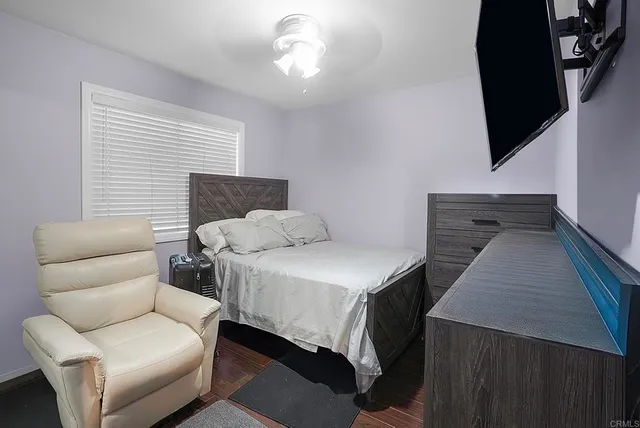 a bedroom with a bed a desk and chair with window