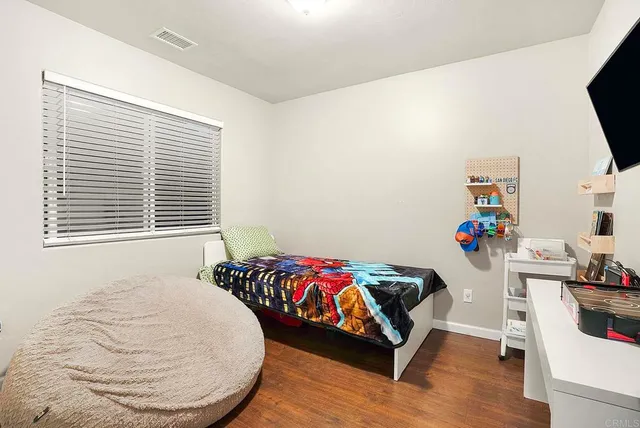 a bedroom with a bed and a flat tv screen on dresser