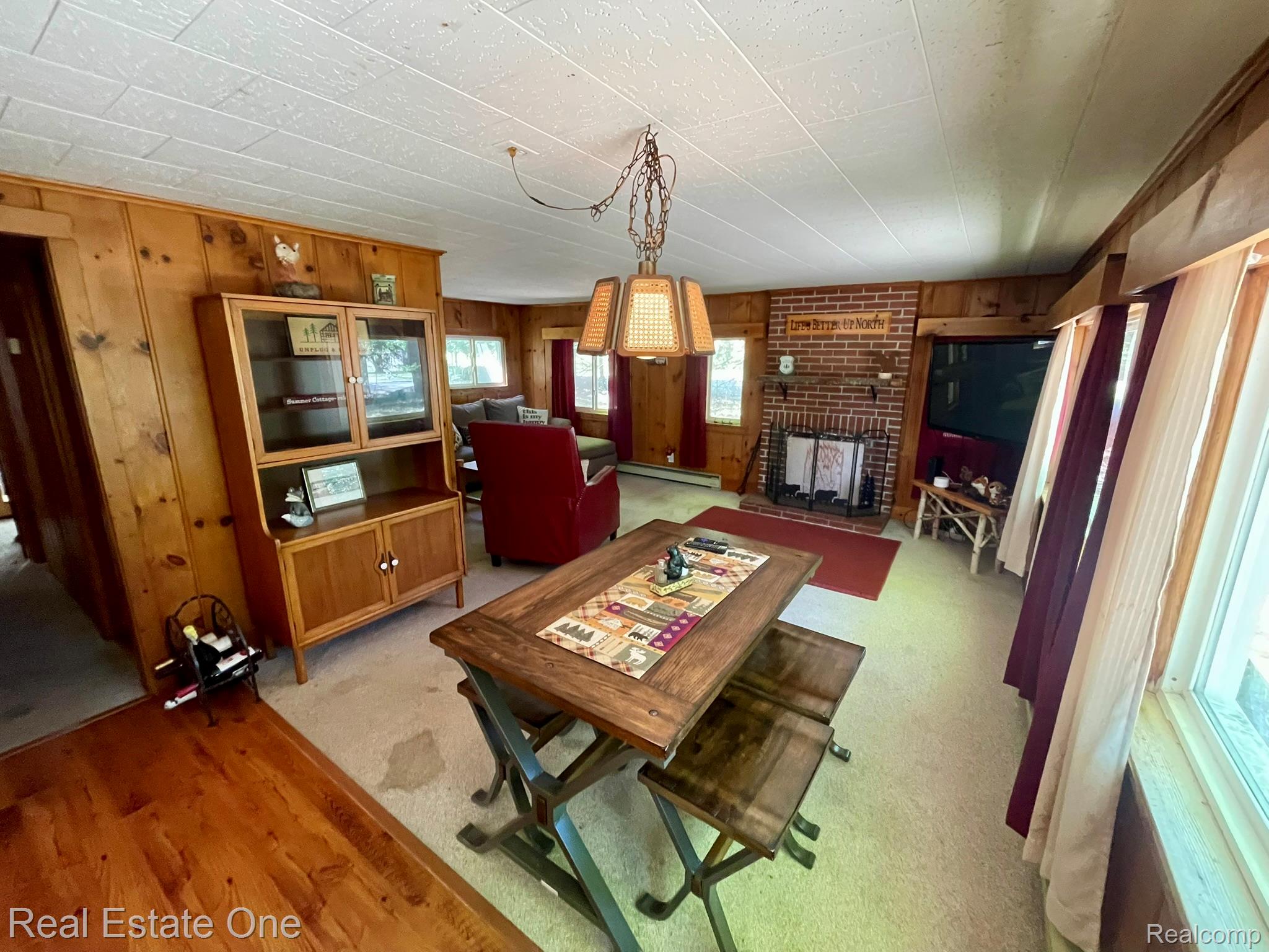 2596 Fox Road Lincoln, MI 48742 - Photo 11 of 54 Living area featuring a brick fireplace with a detailed mantel, wood-finish wall paneling, and a textured white ceiling