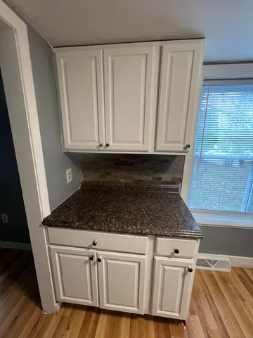 a kitchen with granite countertop white cabinets and sink