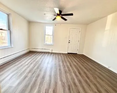 a view of empty room with wooden floor and fan
