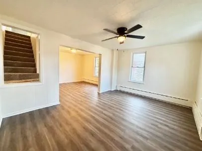 a view of empty room with wooden floor and fan