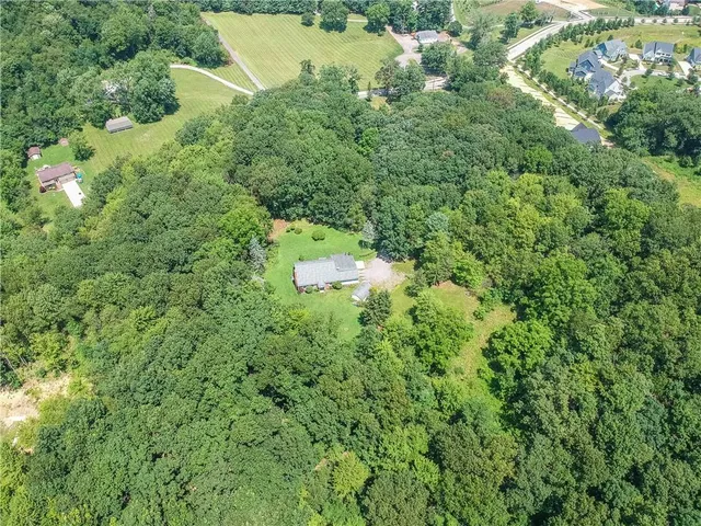 an aerial view of residential house with outdoor space and trees all around