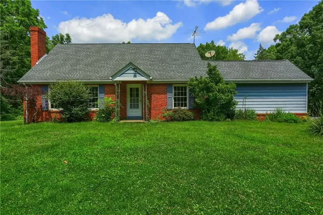 a view of a house with brick walls and a yard with plants