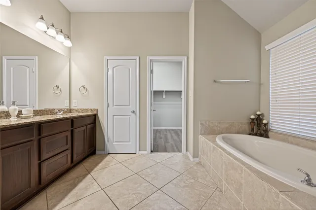 a spacious bathroom with a tub sink and mirror