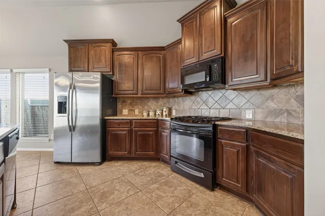 a kitchen with granite countertop a refrigerator stove and microwave