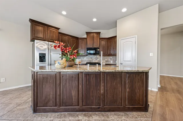 a kitchen with stainless steel appliances granite countertop wooden cabinets a refrigerator and a sink