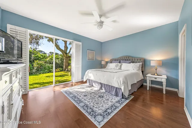 a bedroom with a bed a couch and a large window with wooden floor