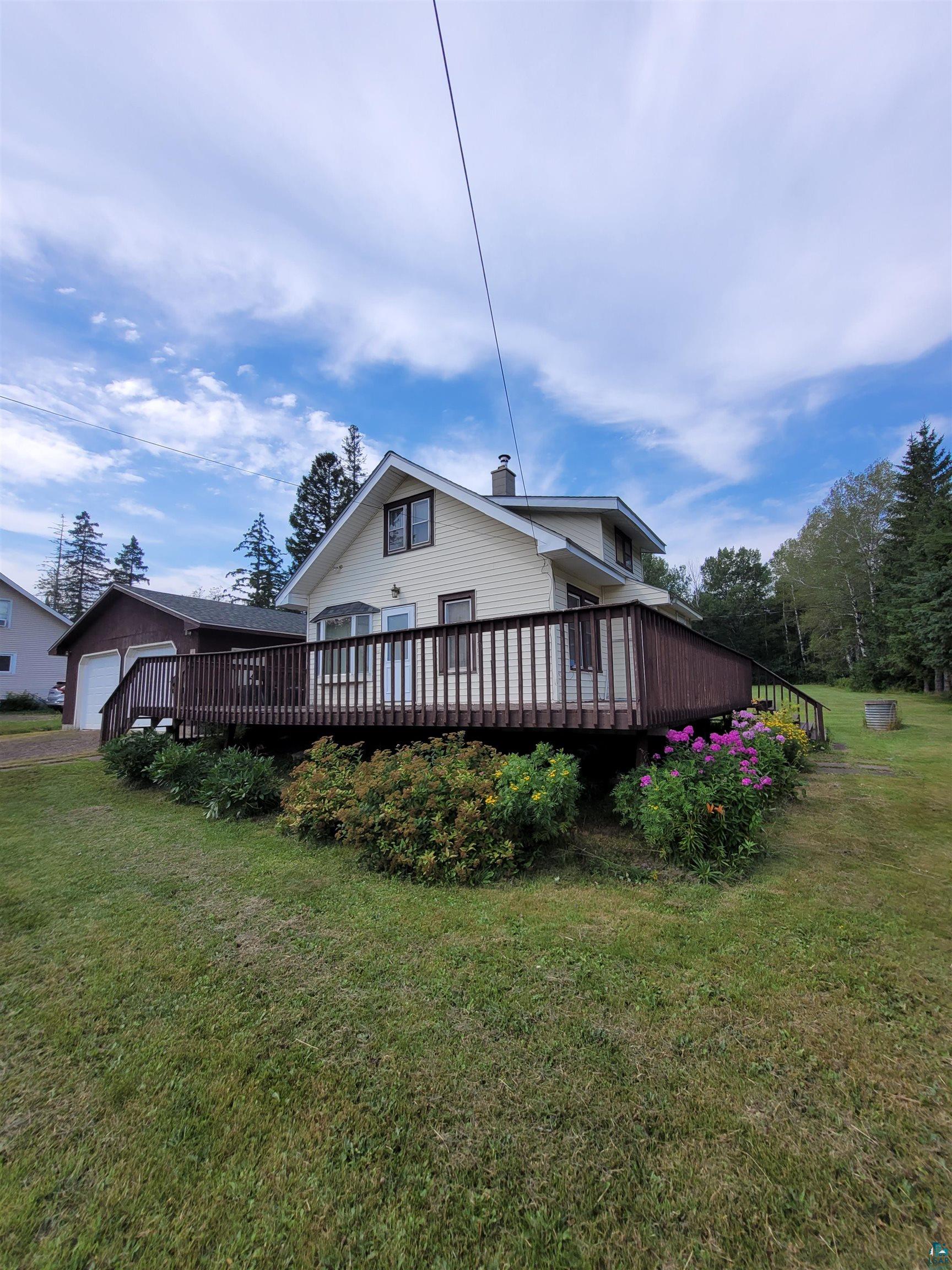 4013 East Calvary Road Duluth, MN 55803 - Photo 2 of 11 View of side of home featuring a deck, an outbuilding, a garage, and a lawn