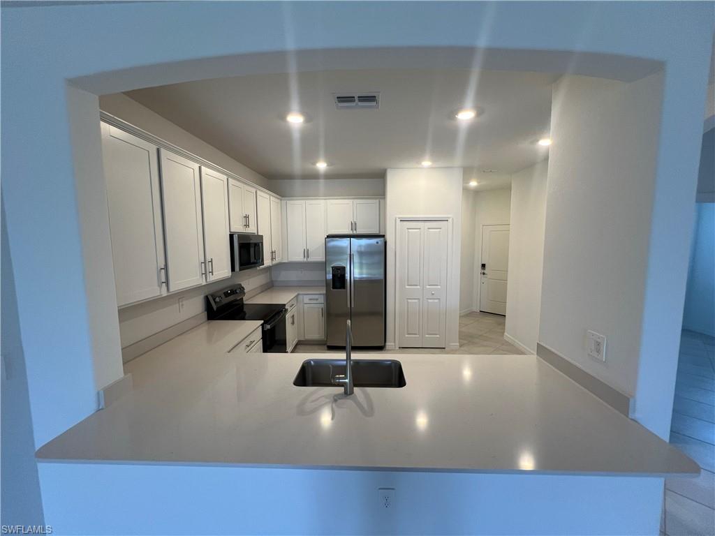 2320 Dragonfruit Way Naples, FL 34120 - Photo 6 of 33 Kitchen with a sink, electric range oven, stainless steel fridge with ice dispenser, visible vents, and recessed lighting