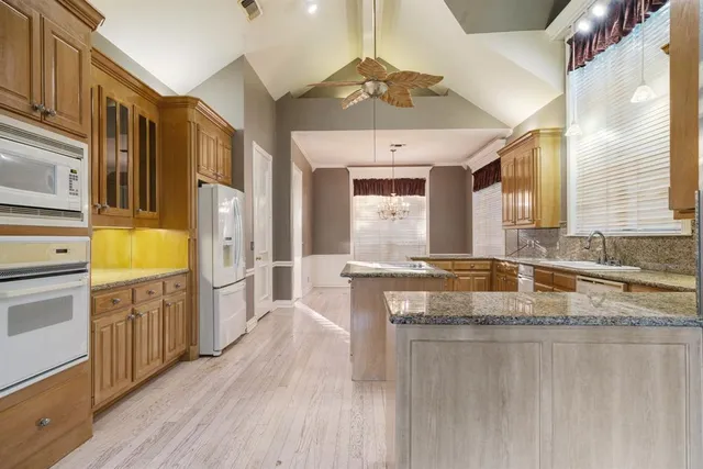 a kitchen with stainless steel appliances granite countertop a sink a stove cabinets and wooden floor