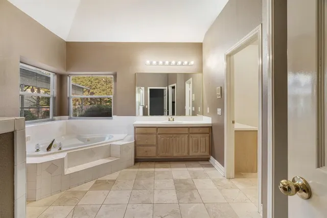 a bathroom with a tub a sink a mirror and a shower