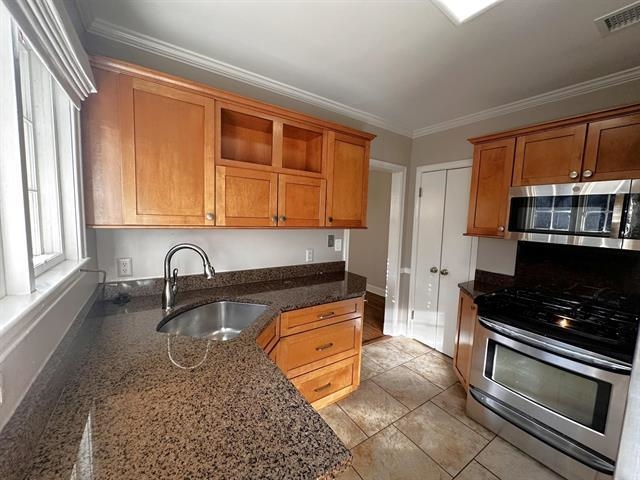 47 North Ashlawn Road Memphis, TN 38112 - Photo 11 of 20 Kitchen with appliances with stainless steel finishes, crown molding, dark stone counters, brown cabinets, and open shelves