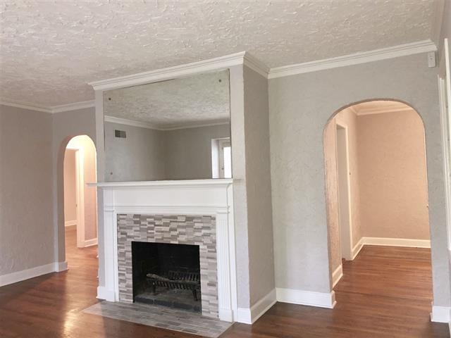 47 North Ashlawn Road Memphis, TN 38112 - Photo 4 of 20 Unfurnished living room with arched walkways, dark wood-style floors, ornamental molding, a tile fireplace, and a textured ceiling
