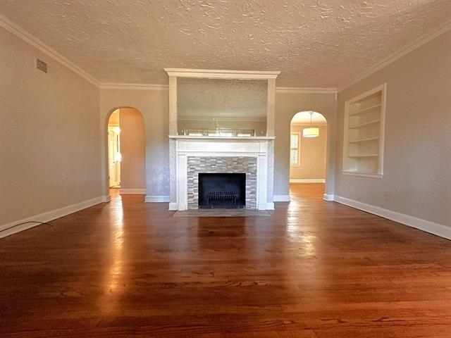 47 North Ashlawn Road Memphis, TN 38112 - Photo 5 of 20 Unfurnished living room featuring arched walkways, built in shelves, dark wood-style floors, a textured ceiling, and crown molding