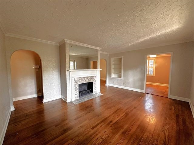 47 North Ashlawn Road Memphis, TN 38112 - Photo 6 of 20 Unfurnished living room featuring arched walkways, dark wood-style floors, a fireplace, and a textured ceiling