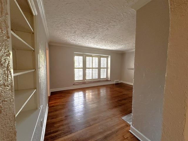 47 North Ashlawn Road Memphis, TN 38112 - Photo 7 of 20 Empty room with wood finished floors, crown molding, a textured ceiling, and a textured wall