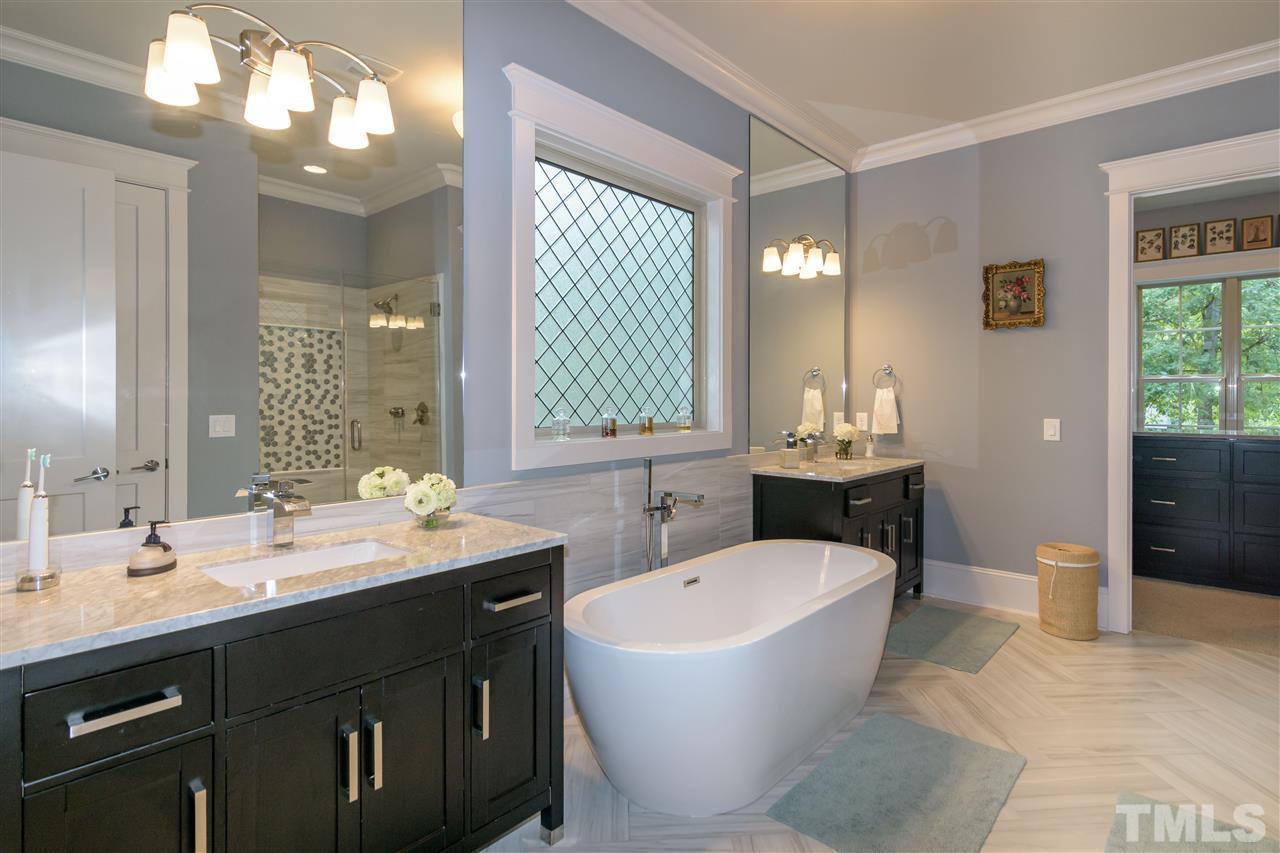 1216 Hunting Ridge Road Raleigh, NC 27615 - Photo 16 of 30 a bathroom with a double vanity sink a mirror and a bathtub
