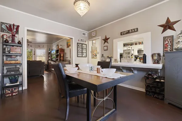 a view of a dining room and livingroom with furniture wooden floor a rug a flat screen tv a painting and a chandelier